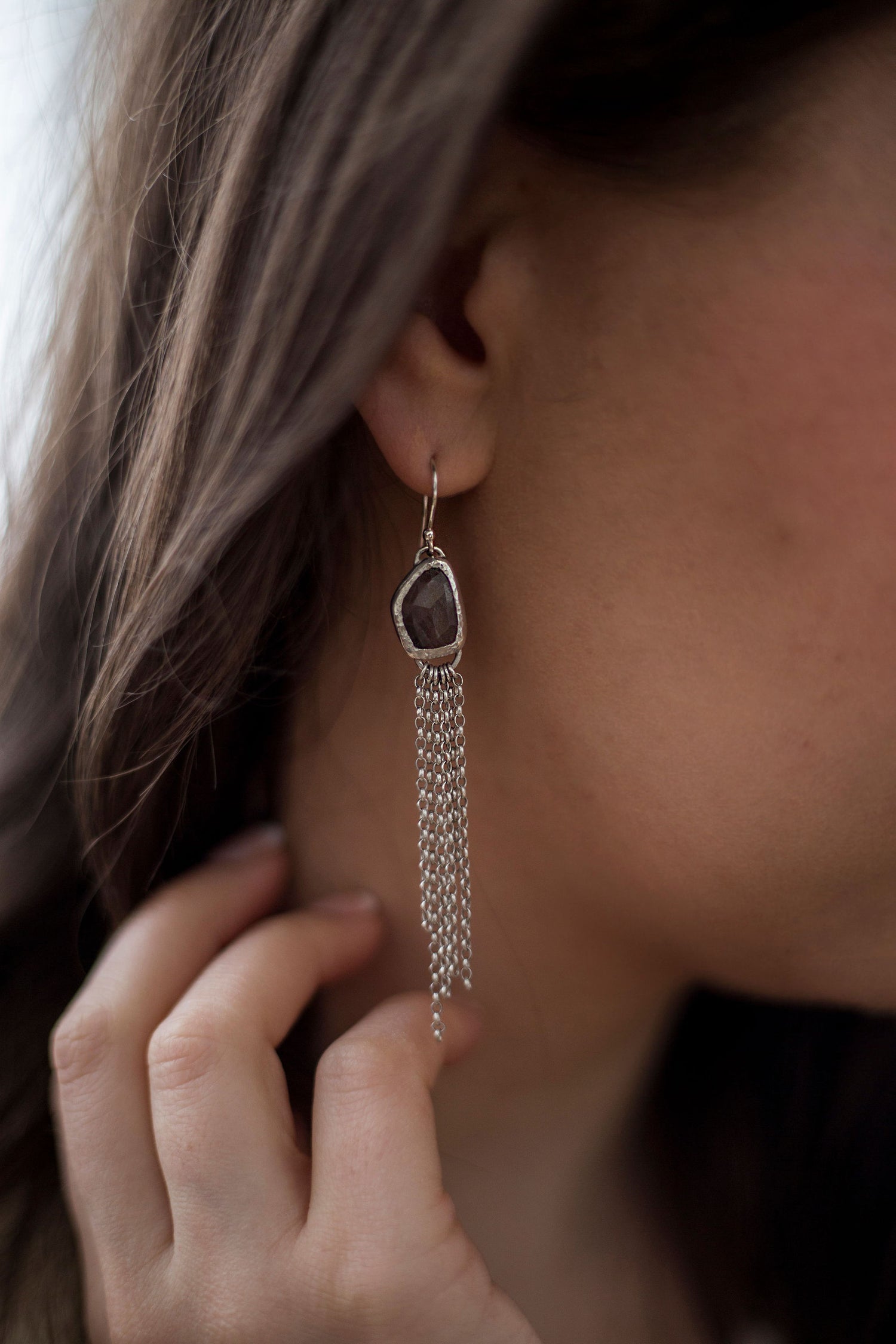 Silver drop earring with large gem stone in a abstract shape with delicate strands of silver chain hanging from the bottom